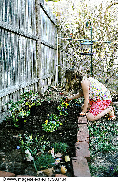 Ein kleines Mädchen kümmert sich um ihr kleines Gartenbeet in ihrem Hinterhof