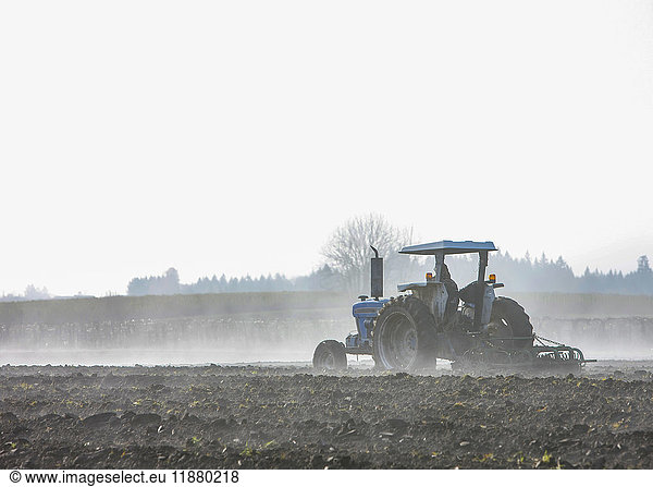 Ein Landwirt pflügt ein Feld mit einem Traktor und einem Pflug