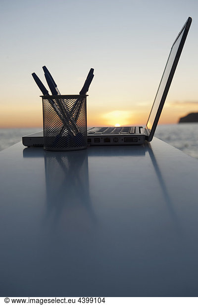 Ein Laptop mit einem Sonnenuntergang dahinter