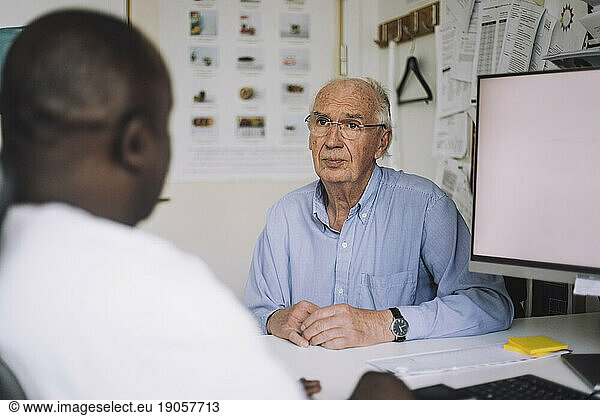 Ein älterer männlicher Patient hört dem Arzt bei einem Besuch in der Klinik zu