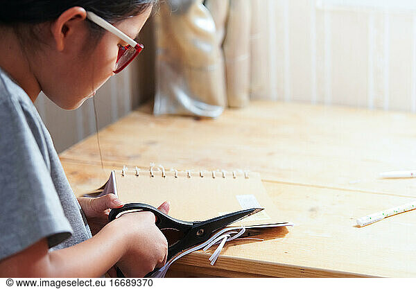 Ein Mädchen schneidet das Handwerksbuch