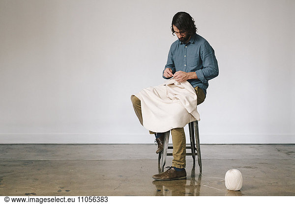 Ein männlicher Künstler arbeitet  häkelt mit Schnur und schafft ein Kunstwerk.