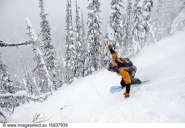 Ein männlicher Snowoarder findet im kanadischen Hinterland Tiefschnee.