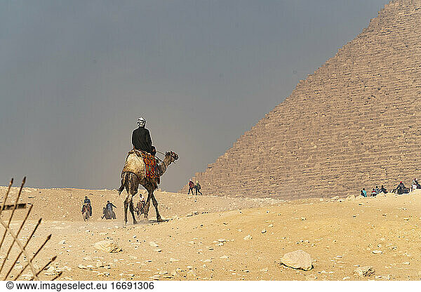 Ein Mann auf einem Kamel reitet in Richtung der großen Pyramide von Gizeh  Ägypten