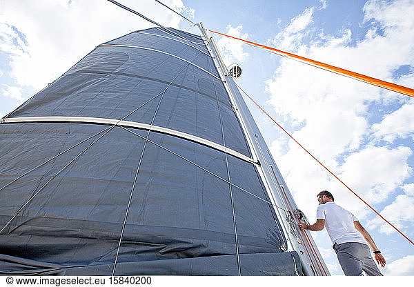 Ein Mann bei einem Manöver am Mast eines Kreuzfahrt-Katamarans