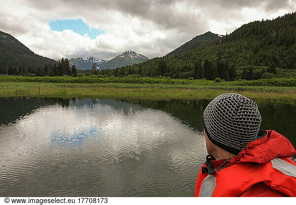 Ein Mann blickt auf die Berge  die Landschaft und das Wasser vor ihm; Inside Passage  Alaska