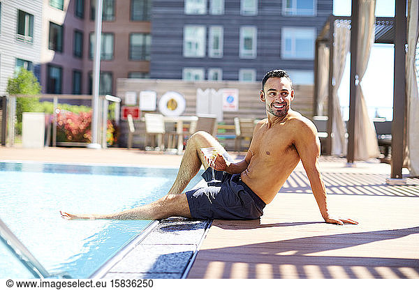 Ein Mann entspannt sich bei einem Drink am Pool.