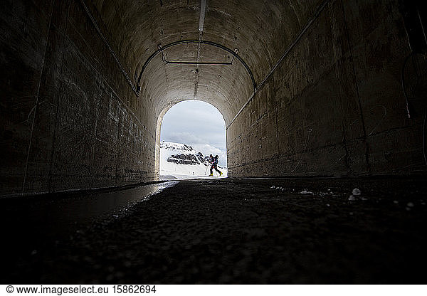 Ein Mann fährt auf Skiern an einem Tunnel in Island vorbei.