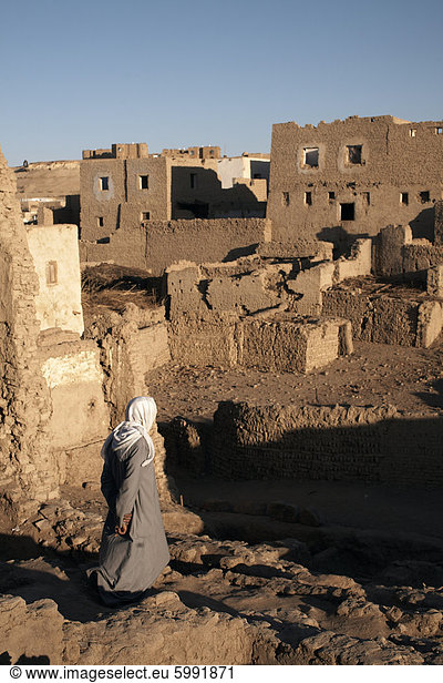 Ein Mann hebt sich die Ruine der Stadt Lehmziegeln Al-Qasr  Oase Dakhla  Ägypten  Nordafrika  Afrika
