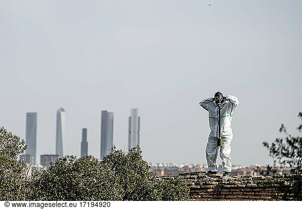 Ein Mann in einem EPI-Virus-Anzug und einer Gasmaske im Gesicht mit der Stadt im Hintergrund