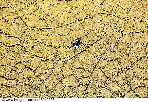 Ein Mann liegt auf einem von der Dürre gezeichneten Boden. Gebiet des Yesa-Stausees. Zaragoza  Aragon  Spanien  Europa.