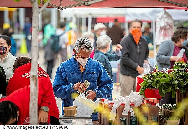 Ein Mann mit Gesichtsmaske holt auf dem Silver Spring Farmers Market  Silver Spring  MD  Bargeld heraus.