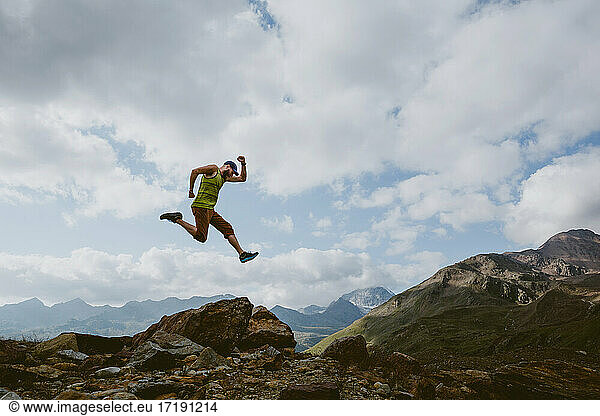 Ein Mann springt vor einer Berglandschaft in die Luft
