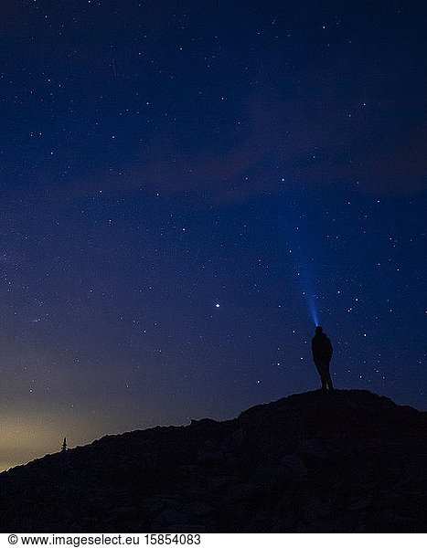 Ein Mann starrt mit einem Scheinwerfer in den Nachthimmel.