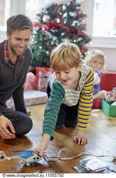 Ein Mann und zwei Kinder finden und packen am Weihnachtstag Geschenke aus.