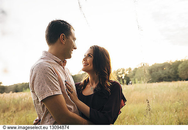 Ein Paar sieht sich an  während es auf einem Grasfeld vor klarem Himmel steht