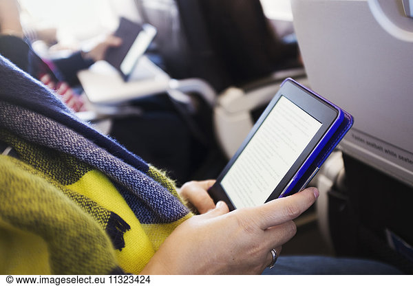 Ein Passagier in einem Flugzeug  der ein digitales Tablett benutzt.