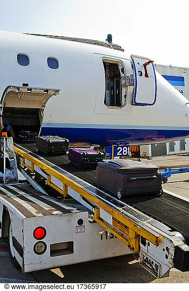 Ein Passagierflugzeug am Boden  das Gepäck wird auf ein laufendes Band geladen