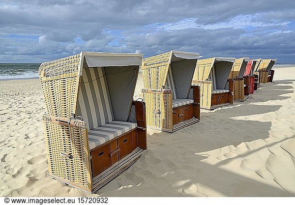 Ein roter Strandkorb zwischen einer Reihe von beigen Strandkörben am Sandstrand,  Sylt,  Nordfriesische Insel,  Nordfriesland,  Schleswig-Holstein,  Deutschland,  Europa