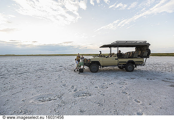 Ein Safarifahrzeug  das in der Abenddämmerung in der Salinenlandschaft geparkt ist.