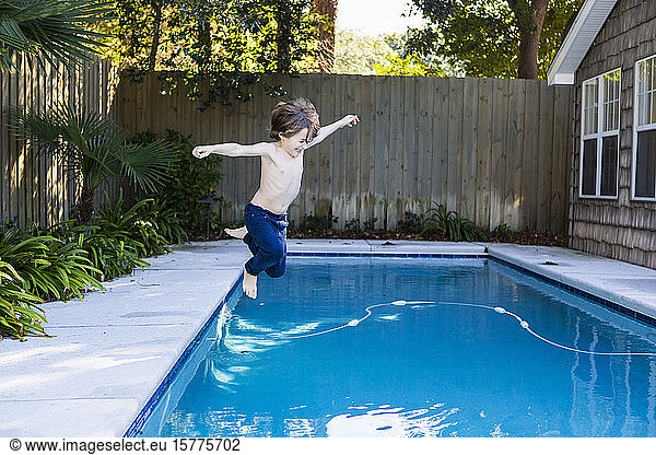 Ein sechsjähriger Junge springt in ein Schwimmbecken