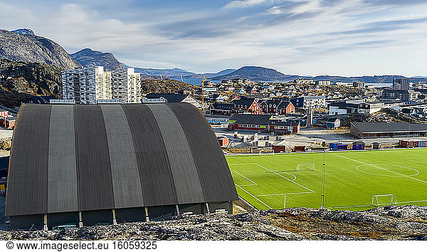 Ein Sportplatz und ein Bauwerk mit Blick auf eine Nachbarschaft und die Berge; Nuuk  Sermersooq  Grönland