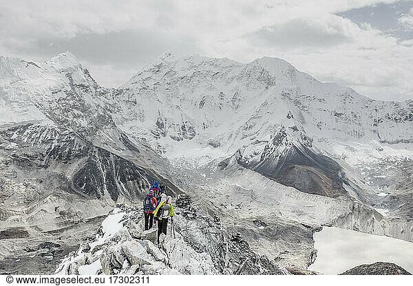 Ein Team von Alpinisten überquert einen felsigen Grat auf dem Island Peak