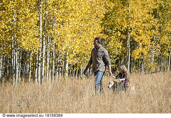 Ein Vater und seine Tochter wandern durch einen Aspen-Hain.