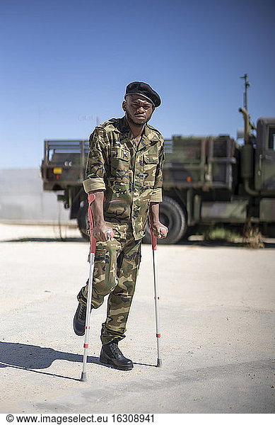Ein verletzter Soldat steht mit Krücken an einem sonnigen Tag