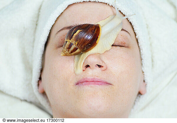 Eine 40-jährige Frau verjüngt ihr Gesicht mit einer Schnecke Tier,wirbelloses Tier,Weichtier ...