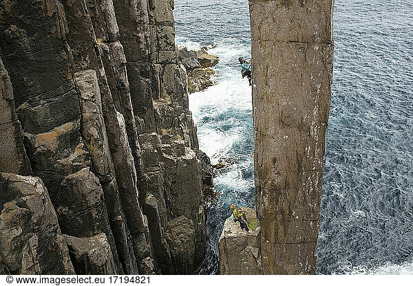 Eine abenteuerlustige Frau klettert mit ihrem Partner in Australien auf einen Felsvorsprung.