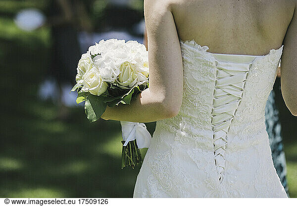 Eine Braut in einem weißen Kleid mit eng anliegendem Mieder und Schnürungen an den Rückenteilen.