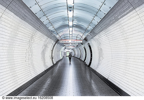 Eine einzelne Person  die während der Coronavirus-Sperre einen Korridor in einer U-Bahn-Station entlangläuft  London  England  Vereinigtes Königreich  Europa