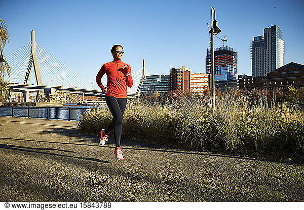 Eine fitte Frau rennt an der Skyline von Boston vorbei.