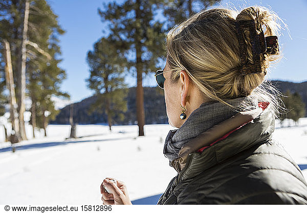 Eine Frau betrachtet eine schöne Schneelandschaft mit Kiefern.