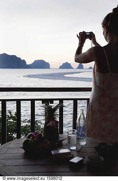 Eine Frau fotografieren die Sicht über den Ozean von einem Balkon in Thailand.