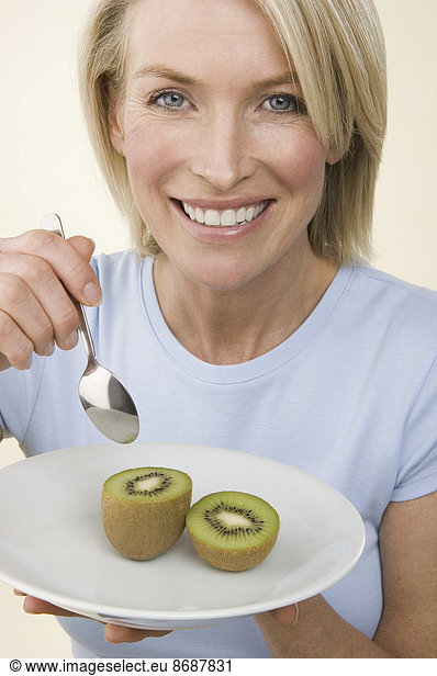 Eine Frau isst eine Kiwifrucht.