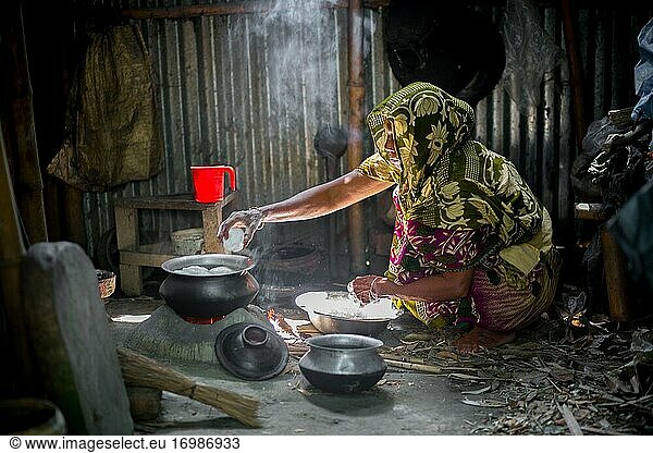 Eine Frau kocht Reisbällchen auf einem traditionellen  mit Holzkohle befeuerten Lehmofen in Narsingdi  Bangladesch.