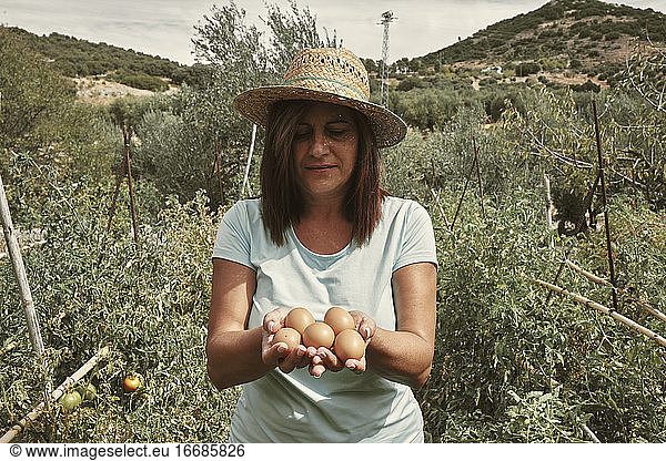 Eine Frau mit Eiern in den Händen  die sie in ihrem eigenen Betrieb gesammelt hat