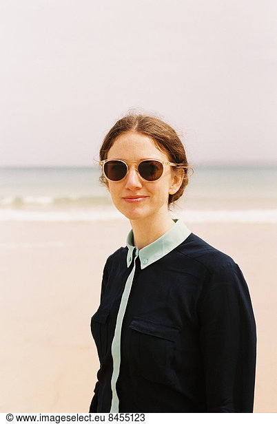 Eine Frau mit Sonnenbrille am Strand.