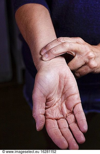 Eine Frau prüft ihren Puls mit den Fingern.