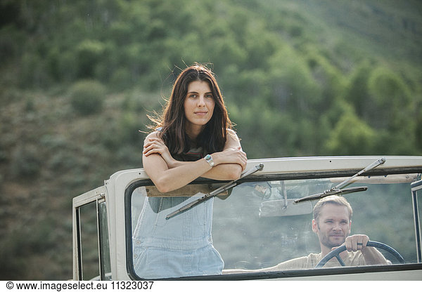 Eine Frau steht in einem Jeep auf und sieht sich in der Landschaft um.