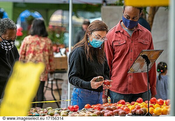 Eine Frau und ein Mann mit Maske haben auf dem Silver Spring Farmers Market in Silver Spring  MD  Tomaten zum Verkauf angeboten.