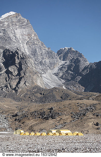 Eine Gruppe orangefarbener Zelte in einem Basislager für Bergsteiger in der Himalaya-Region.