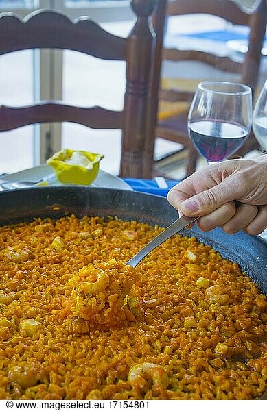 Eine Hand serviert Paella. Valencia  Spanien.