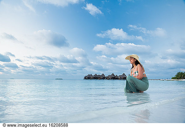Eine indische Touristin am blauen Wasser und weißen Sandstrand  Die Malediven  Indischer Ozean  Asien