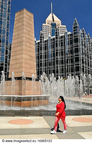 Eine junge Frau schlendert während der Mittagspause in Pittsburgh  Pennsylvania  um den Springbrunnen am PPG Plaza herum.