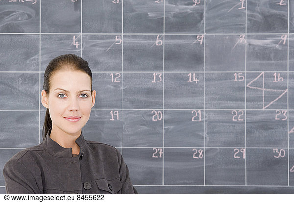 Eine junge Frau vor einer als Kalender gezeichneten Tafel.