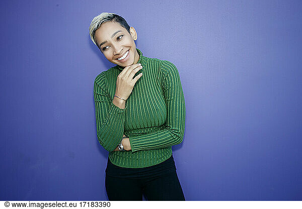 Eine junge schwarze Frau mit einem schüchternen Lächeln vor einem schlichten Hintergrund