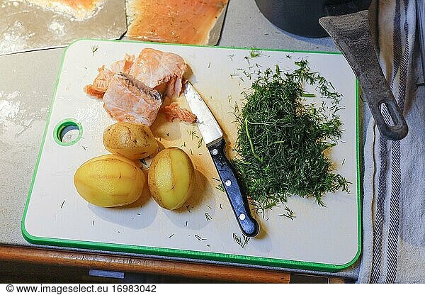 Eine Küchenarbeitsplatte mit den Zutaten für den klassischen schwedischen Laxpudding: Kartoffeln  Lax und Dill.